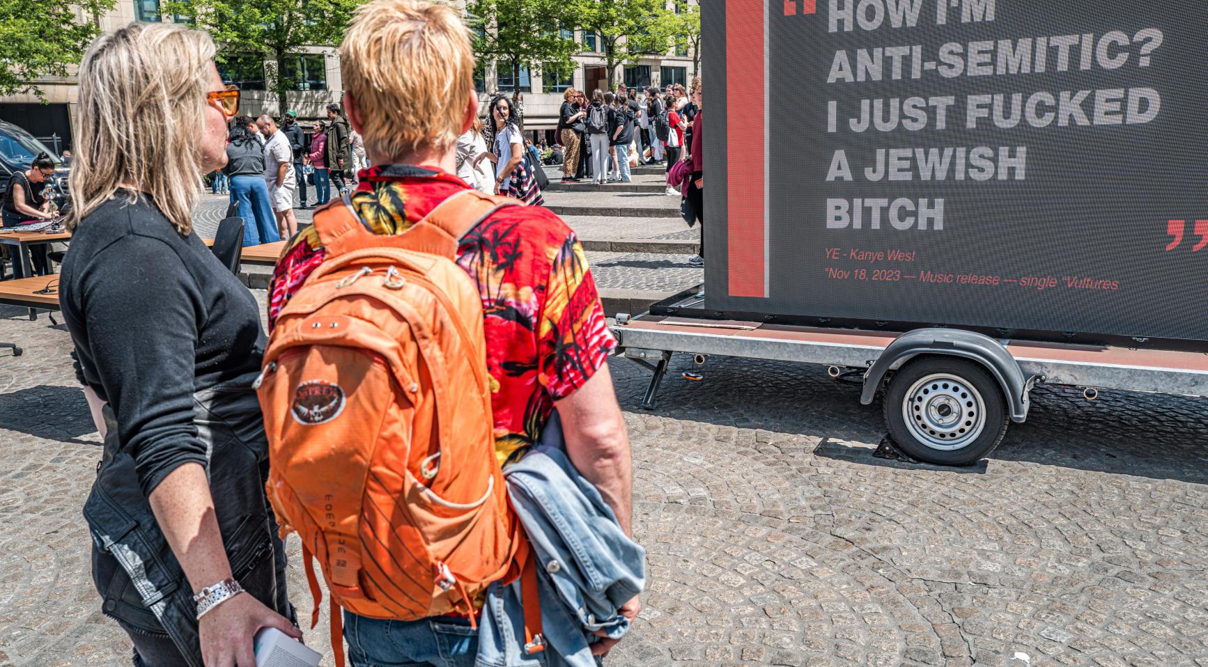 Schermen met Ye-citaten tijdens protest op de Dam tegen concert in Arnhem