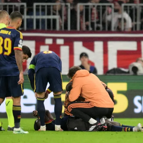 Arsenal-spelers en medische staf staan rond een geblesseerde speler op het veld tijdens een wedstrijd.
