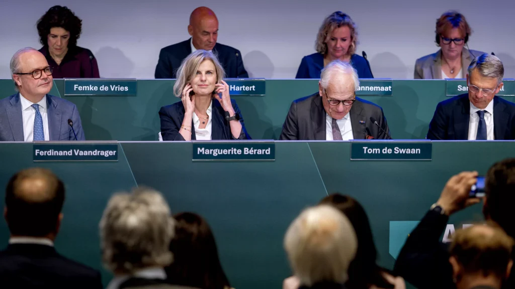 Bestuurspaneel met mannen en vrouwen achter naamplaten tijdens een bijeenkomst.