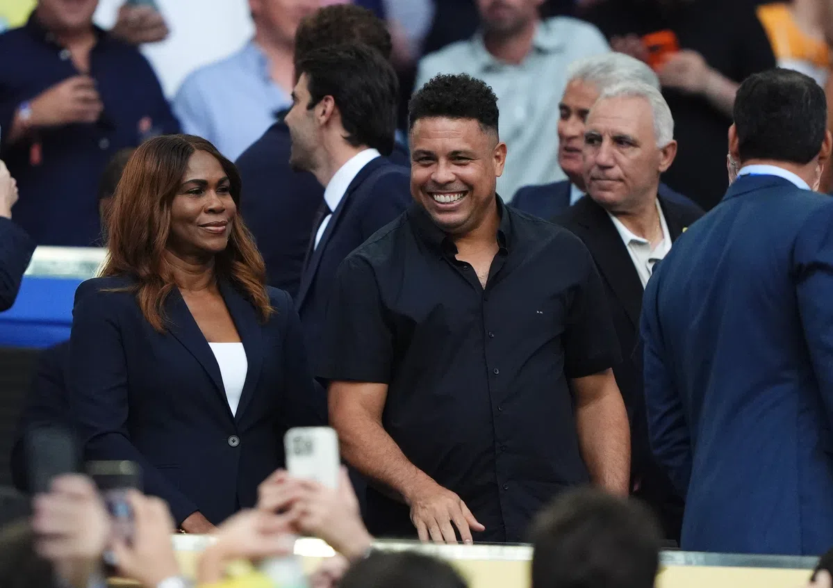Ronaldo Nazário lacht tussen andere aanwezigen op een evenement.