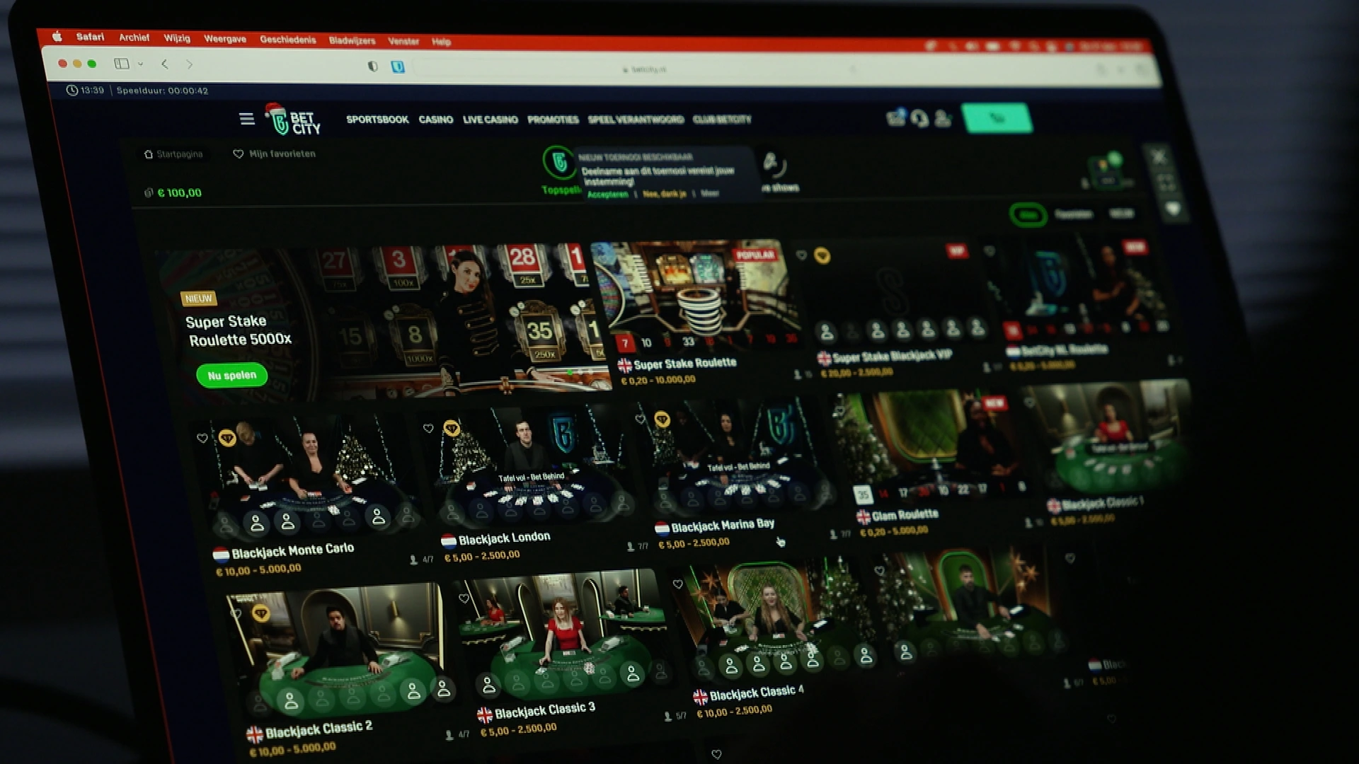 Scherm van een laptop met een online goksite met roulette- en blackjacktafels.