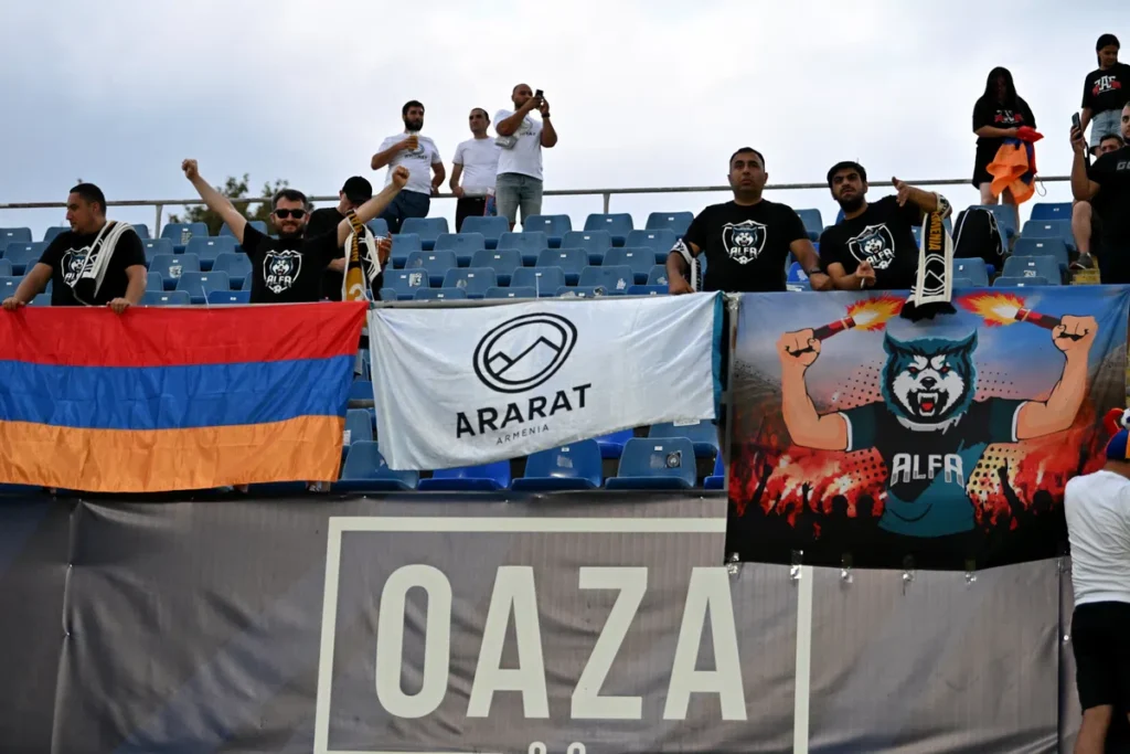 Supporters in a stadium hold banners and flags for Ararat Armenia.