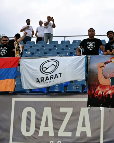 Supporters in a stadium hold banners and flags for Ararat Armenia.