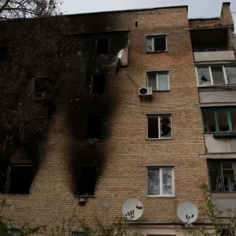 Beschadigd appartementsgebouw met verbrande gevel en kapotte ramen.