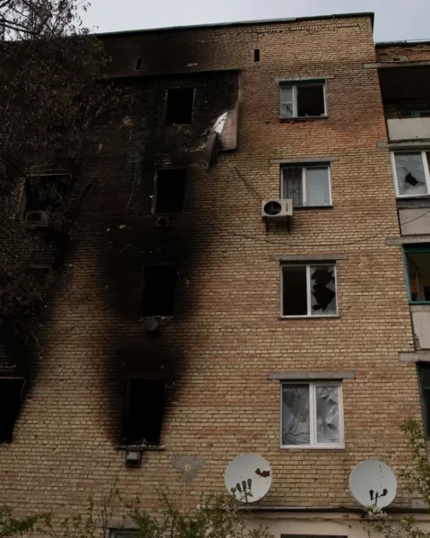 Beschadigd appartementsgebouw met verbrande gevel en kapotte ramen.