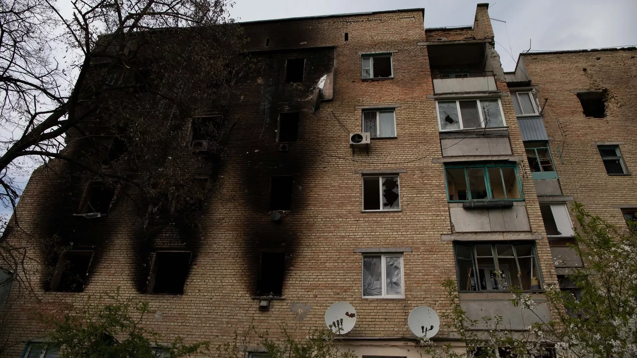 Beschadigd appartementsgebouw met verbrande gevel en kapotte ramen.