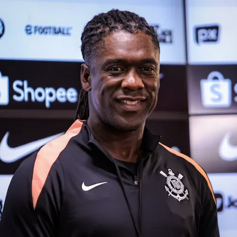 Een Corinthians-figure poseert voor een sponsorwand met clublogo en merklogo’s.