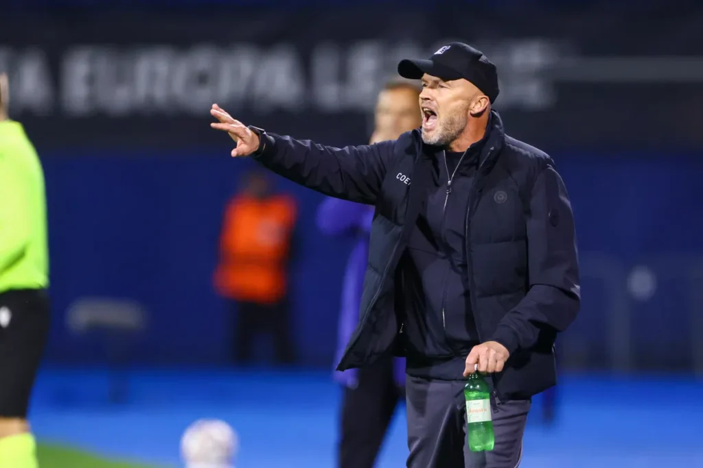 Dick Schreuder geeft aanwijzingen langs de lijn tijdens een voetbalwedstrijd.