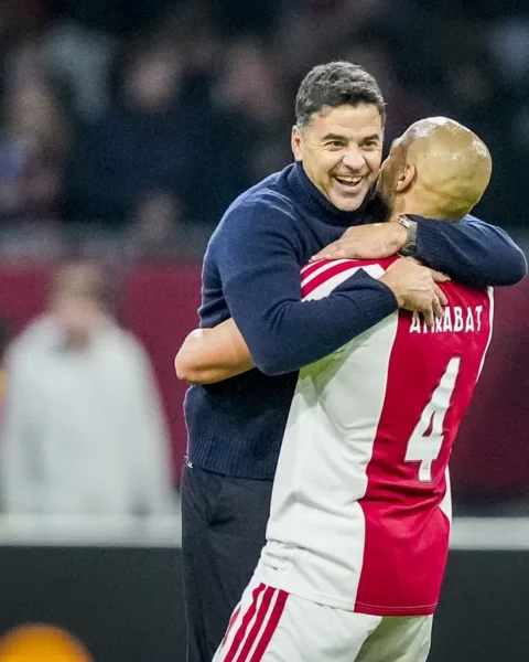 Míchel omhelst een Ajax-speler langs het veld.