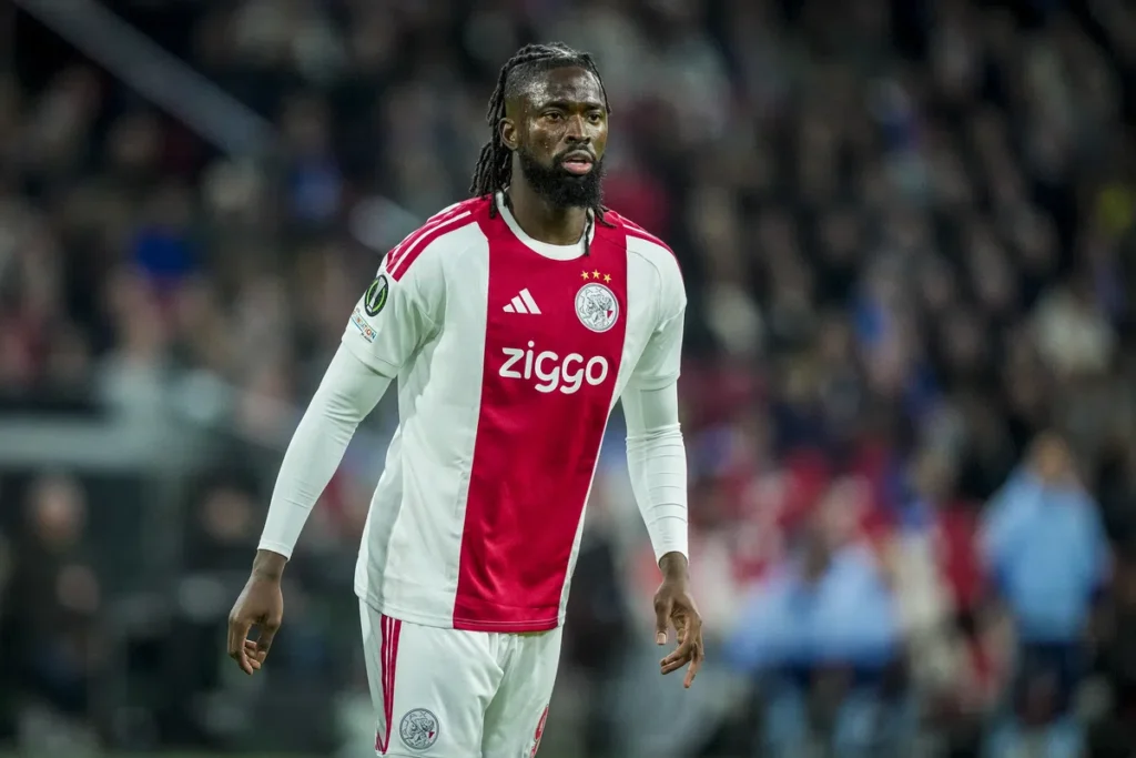 Ajax-speler in wit-rood tenue op het veld tijdens een wedstrijd.