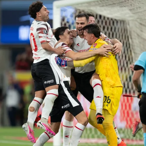 Spelers en de doelman van Estudiantes juichen en omhelzen elkaar naast het doel.