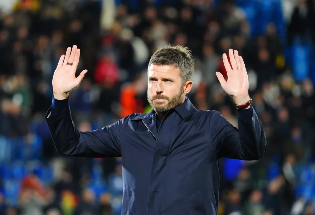 Michael Carrick staat in een stadion met beide handen omhoog.