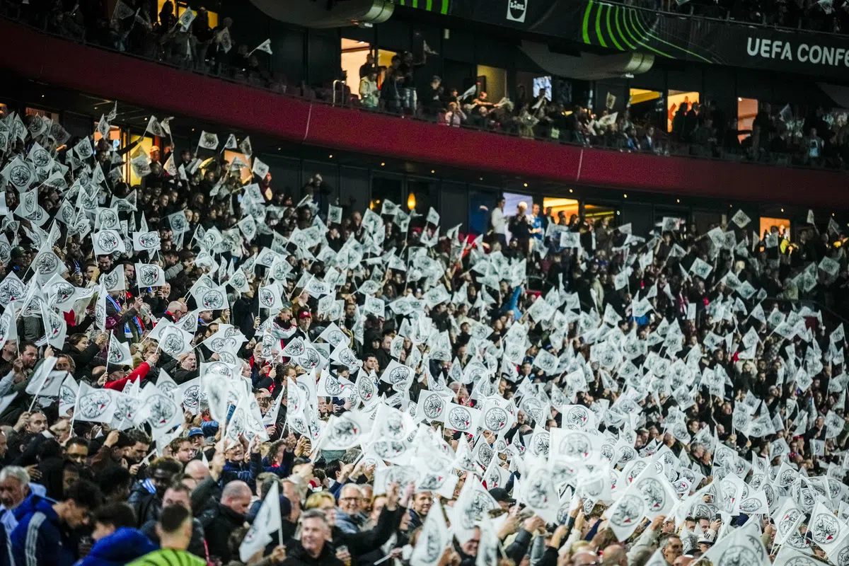 Volgepakte tribunes in een voetbalstadion met veel wapperende witte vlaggen tijdens een Conference League-wedstrijd.