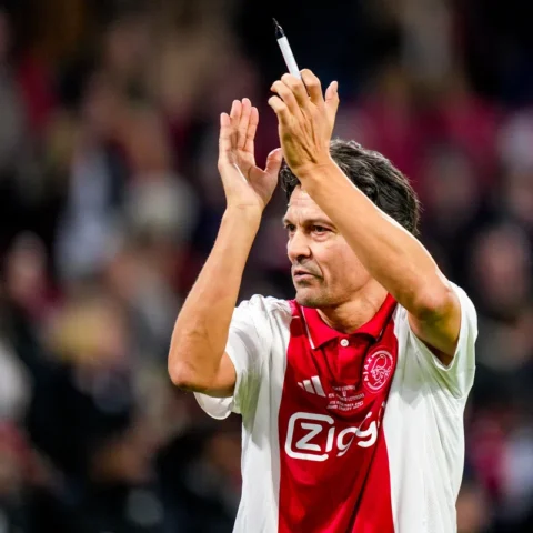 Ajax-icoon applaudisseert op het veld in een Ajax-shirt.