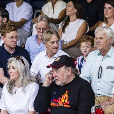 Toeschouwers op de tribune van een stadion, met onder meer een oudere man op de voorgrond.