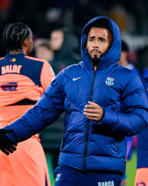 Barcelona-spelers op het veld tijdens een training, met een speler in een blauwe clubjas op de voorgrond.