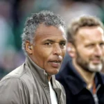 Pierre van Hooijdonk kijkt langs de zijlijn tijdens een voetbalwedstrijd.