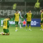 ADO Den Haag-spelers staan op het natte veld na een moment van teleurstelling.