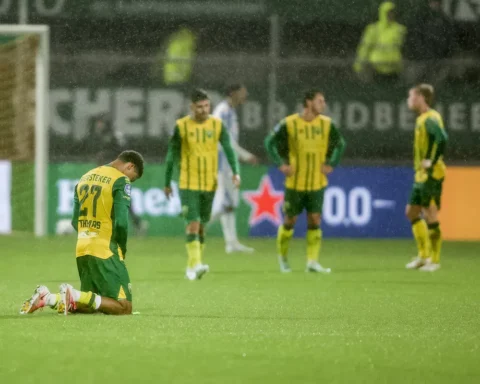 ADO Den Haag-spelers staan op het natte veld na een moment van teleurstelling.