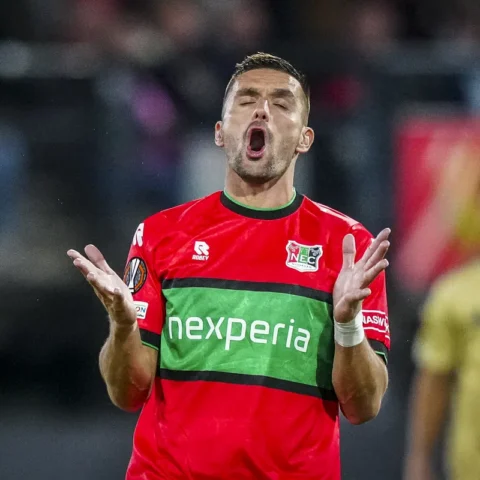 Dusan Tadic van NEC in rood-groen shirt tijdens een wedstrijd, met open mond en geheven handen.