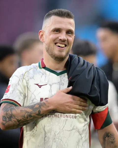 Jeffrey Gouweleeuw lacht op het veld in een FC Augsburg-shirt.