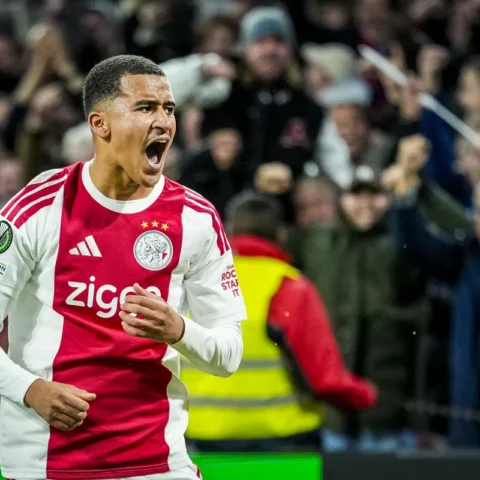 Ajax-speler in rood-wit tenue juicht op het veld.