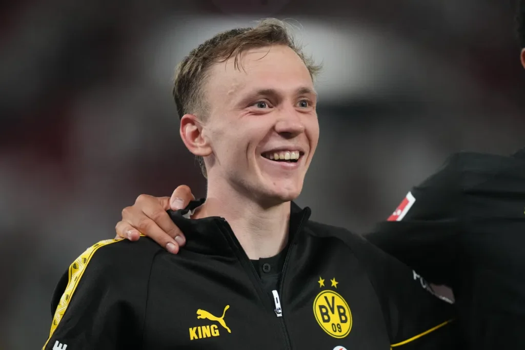 Maximilian Beier lacht in een zwart trainingsjack van Borussia Dortmund.