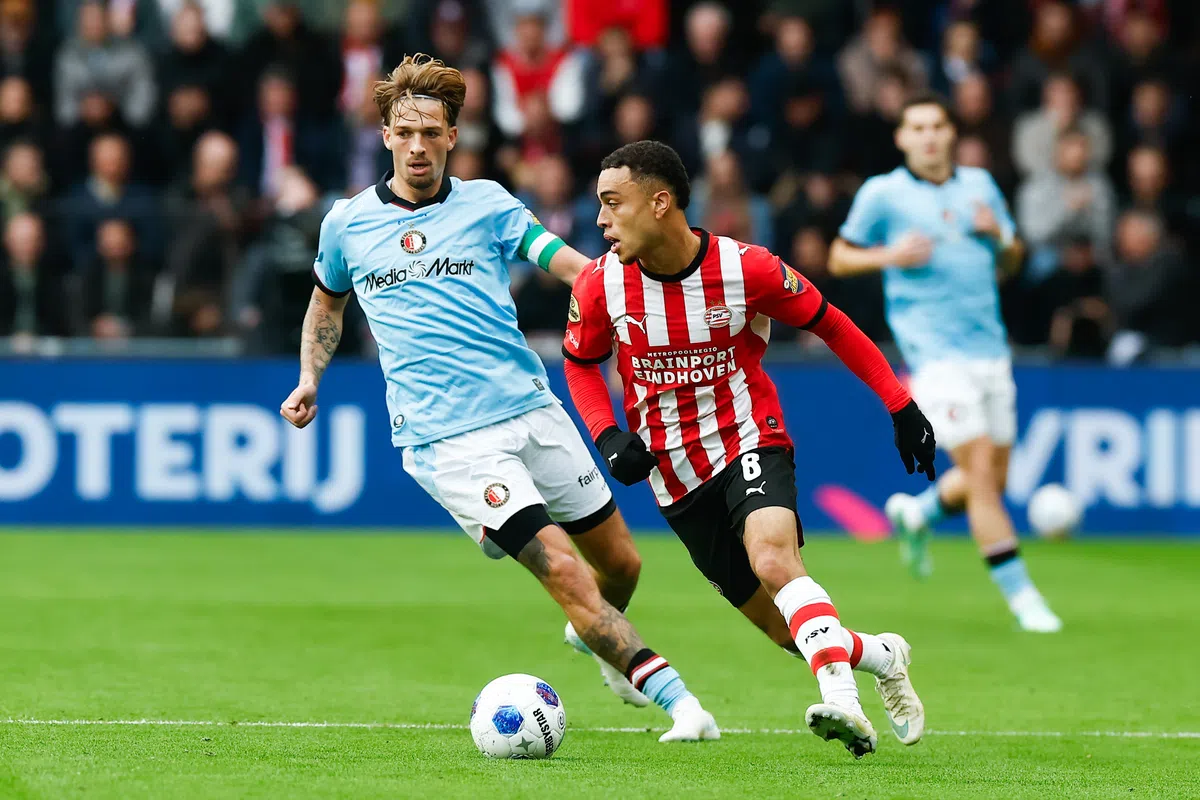 PSV- en Feyenoord-spelers in duel om de bal tijdens een voetbalwedstrijd.