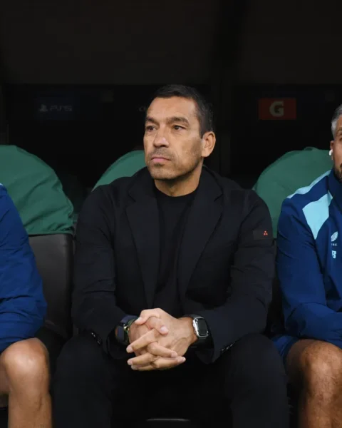 Giovanni van Bronckhorst zit op de bank naast Feyenoord-stafleden tijdens een wedstrijd.
