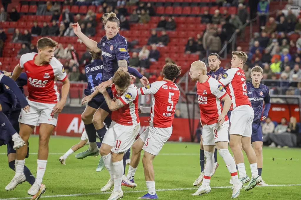 Spelers van AZ en FC Twente springen en duelleren om de bal tijdens een Eredivisie-wedstrijd.