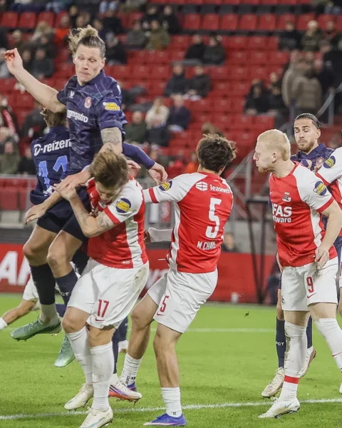 Spelers van AZ en FC Twente springen en duelleren om de bal tijdens een Eredivisie-wedstrijd.