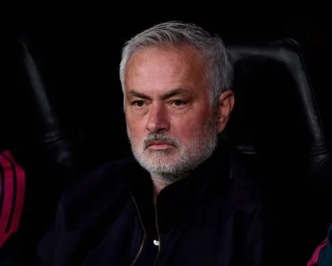 José Mourinho zit op de bank en kijkt ernstig voor zich uit.