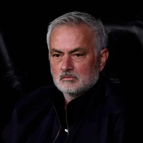 José Mourinho zit op de bank en kijkt ernstig voor zich uit.