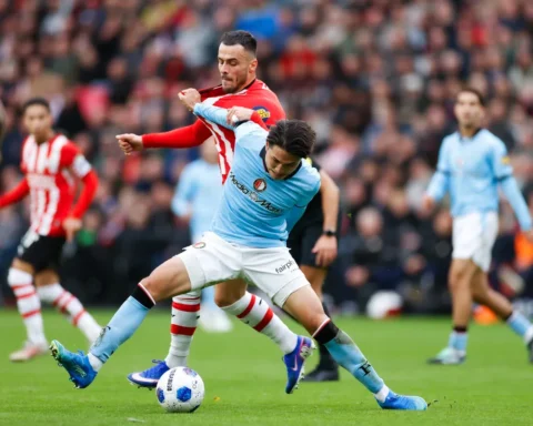 Voetballers van Feyenoord en PSV in duel om de bal op het veld.