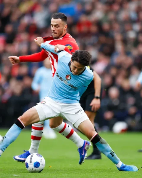 Voetballers van Feyenoord en PSV in duel om de bal op het veld.