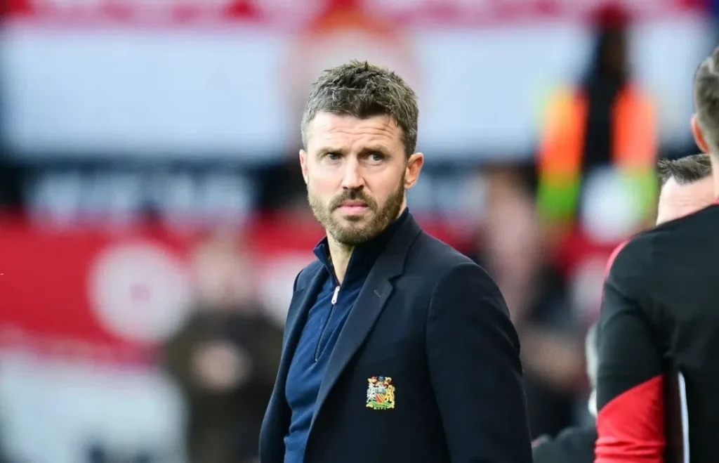 Michael Carrick staat langs de zijlijn in een Manchester United-jasje.