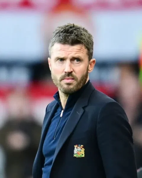 Michael Carrick staat langs de zijlijn in een Manchester United-jasje.
