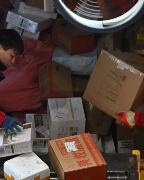 Twee pakketbezorgers laden dozen in een sorteerwagen.