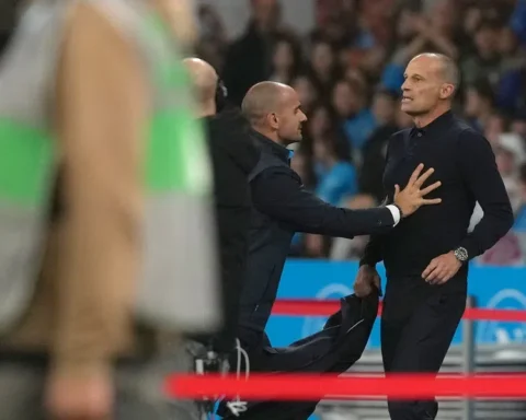 Massimiliano Allegri staat langs de zijlijn tijdens een voetbalwedstrijd terwijl een official hem aanspreekt.