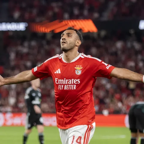Een Benfica-speler viert een doelpunt met uitgestrekte armen in het stadion.