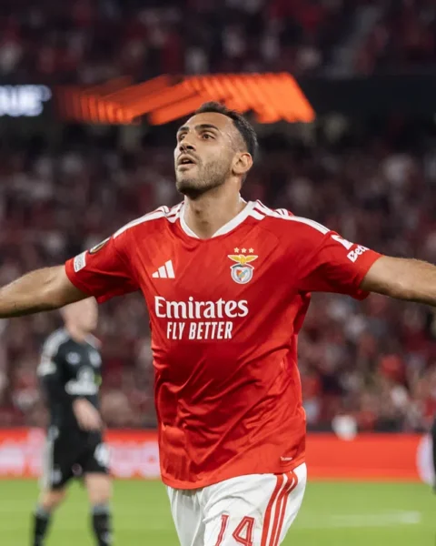 Een Benfica-speler viert een doelpunt met uitgestrekte armen in het stadion.