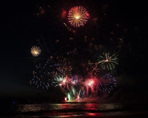 Vuurwerk explodeert boven water in de nachtelijke hemel.