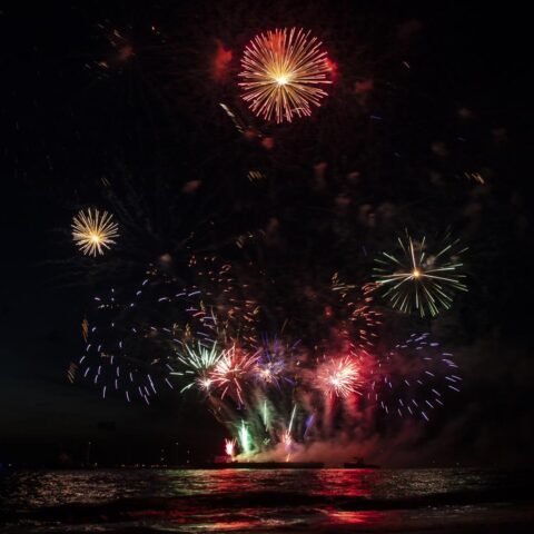 Vuurwerk explodeert boven water in de nachtelijke hemel.