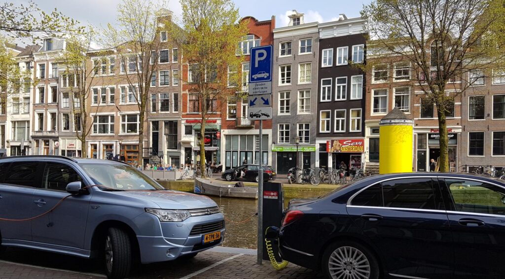 Geparkeerde auto's langs een Amsterdamse gracht met een parkeersignaal op straat.