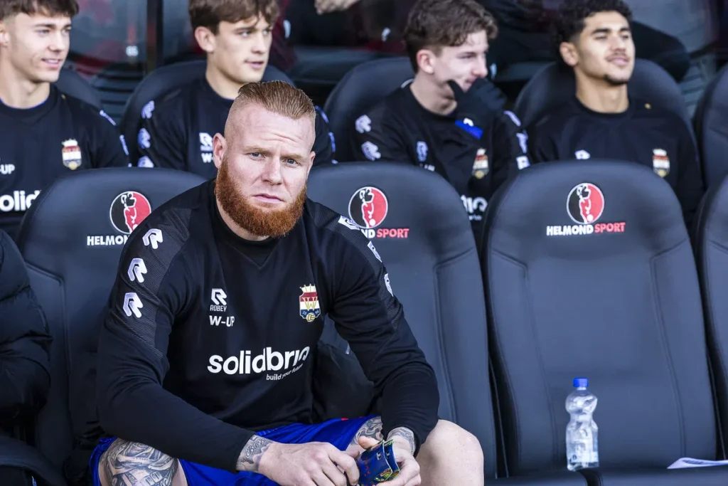 Thomas Verheydt zit op de bank in het stadion van Helmond Sport in zwart trainingsshirt.