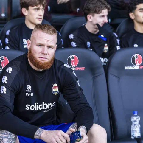 Thomas Verheydt zit op de bank in het stadion van Helmond Sport in zwart trainingsshirt.