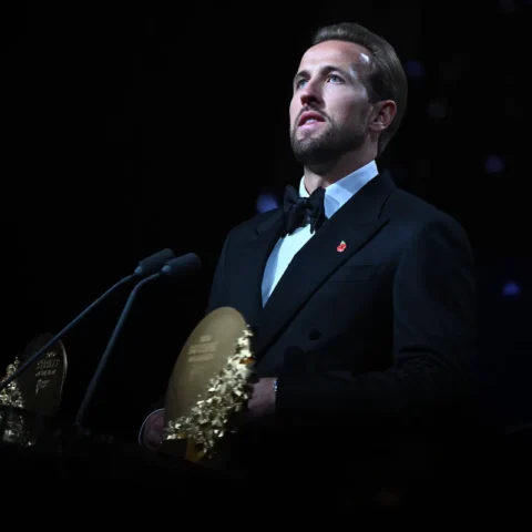 Harry Kane in een zwart smokingpak bij een podium tijdens een prijsuitreiking.