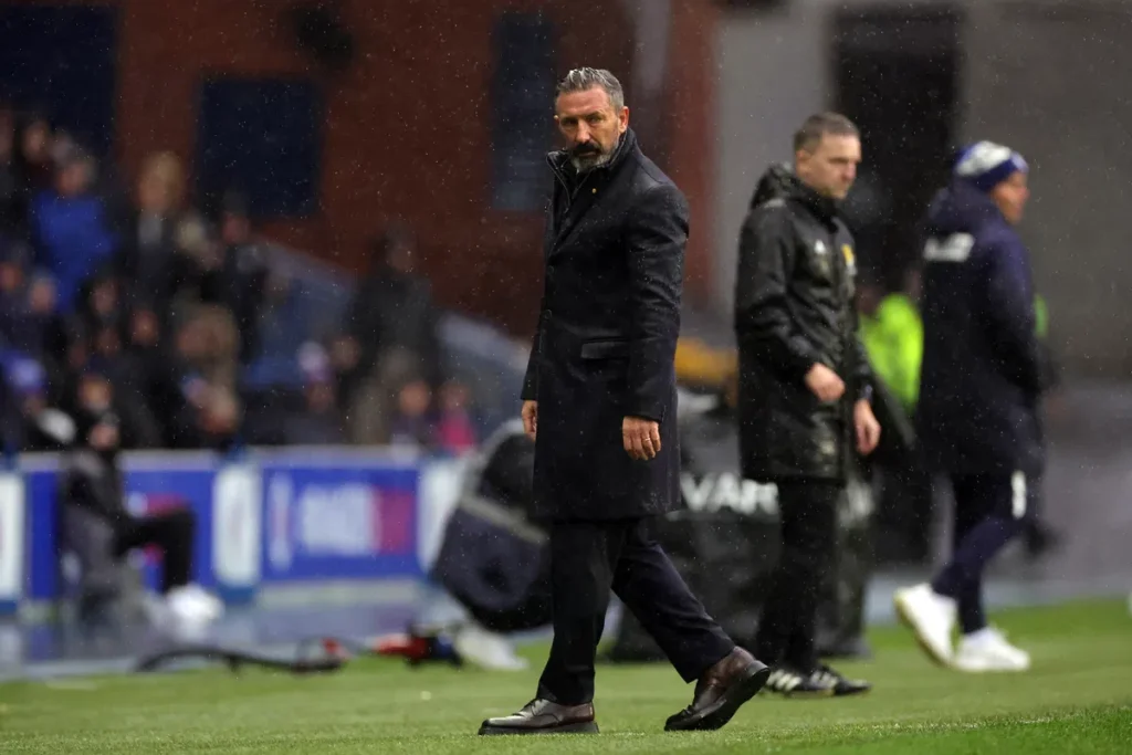 Derek McInnes staat langs de zijlijn op een nat voetbalveld.