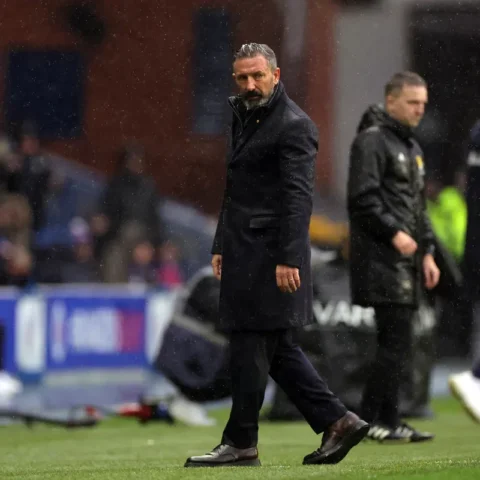Derek McInnes staat langs de zijlijn op een nat voetbalveld.