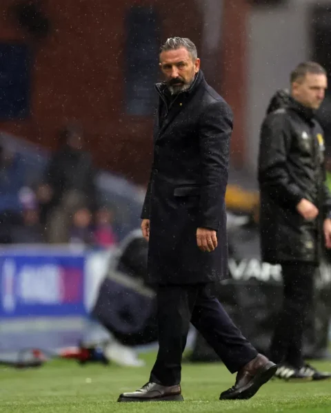 Derek McInnes staat langs de zijlijn op een nat voetbalveld.